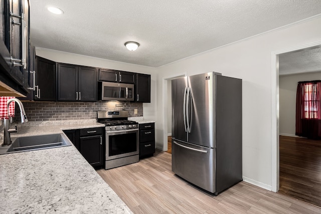 kitchen featuring sink, light hardwood / wood-style flooring, tasteful backsplash, and stainless steel appliances