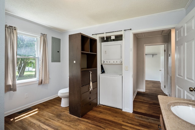 bathroom featuring toilet, vanity, hardwood / wood-style floors, a textured ceiling, and stacked washer / drying machine