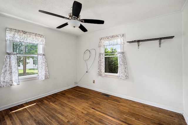 empty room featuring plenty of natural light, ceiling fan, and dark hardwood / wood-style flooring