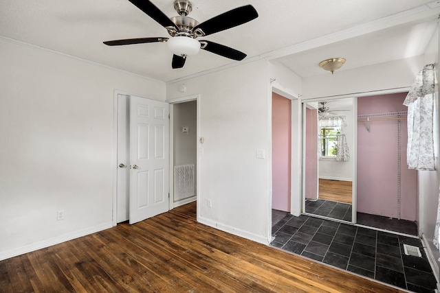 unfurnished bedroom featuring dark tile flooring, a closet, and ceiling fan