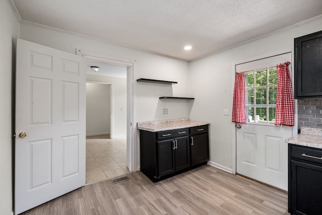 kitchen featuring a textured ceiling, crown molding, backsplash, and light hardwood / wood-style flooring