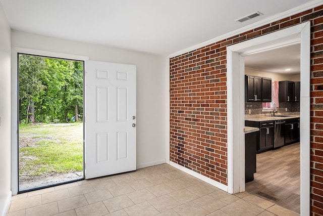 interior space with brick wall, crown molding, sink, and light wood-type flooring