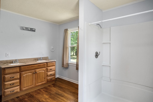 bathroom featuring a textured ceiling, double sink vanity, hardwood / wood-style flooring, and crown molding