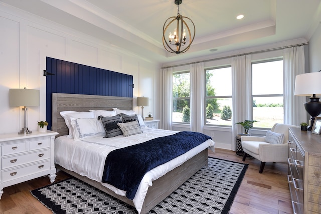 bedroom featuring a raised ceiling, dark wood-type flooring, and an inviting chandelier