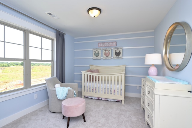 bedroom featuring a nursery area and light colored carpet