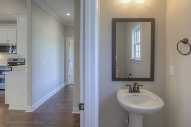 bathroom with backsplash, crown molding, sink, and wood-type flooring