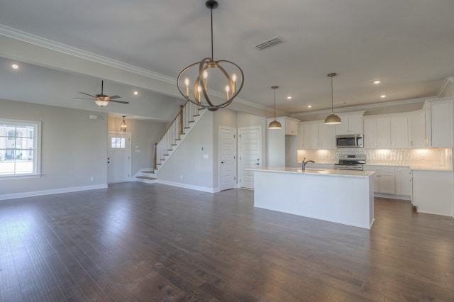 kitchen with pendant lighting, dark wood-type flooring, stainless steel appliances, ceiling fan with notable chandelier, and white cabinets