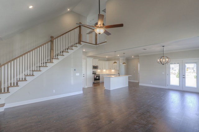 unfurnished living room featuring french doors, crown molding, dark hardwood / wood-style floors, ceiling fan with notable chandelier, and a high ceiling