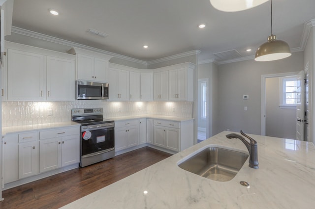 kitchen featuring dark hardwood / wood-style floors, sink, white cabinets, appliances with stainless steel finishes, and decorative light fixtures