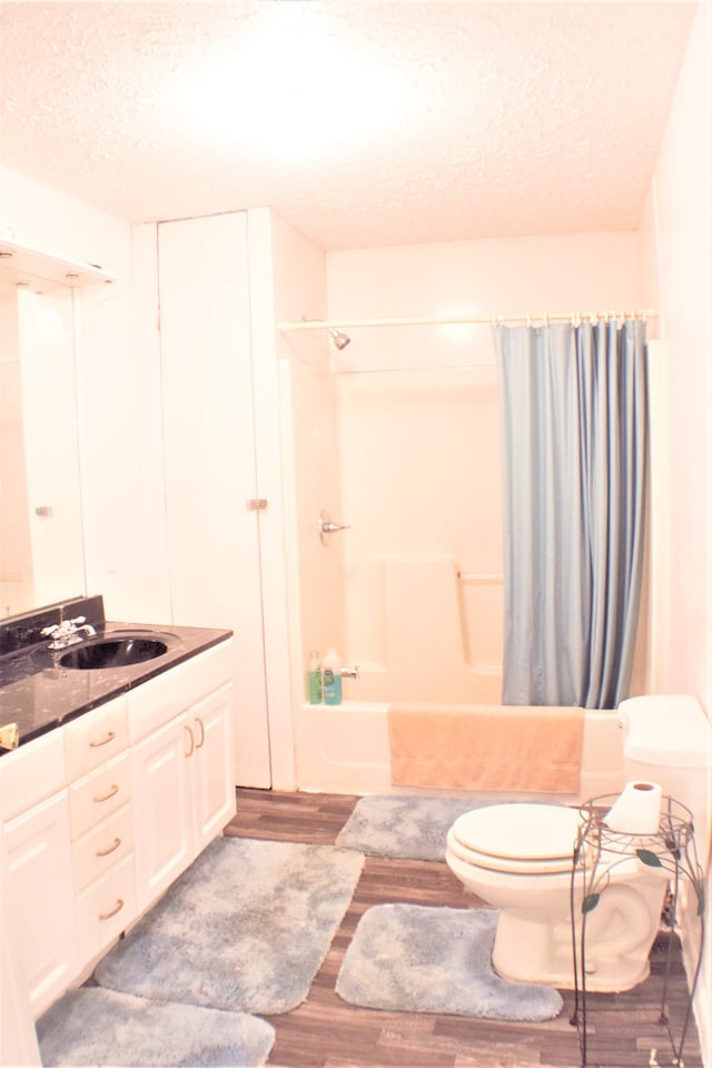 full bathroom featuring wood-type flooring, a textured ceiling, toilet, vanity, and shower / bath combo