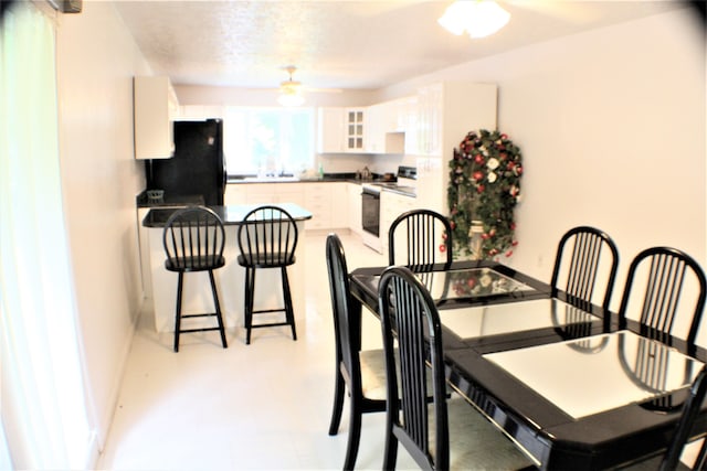 tiled dining space with a textured ceiling and ceiling fan