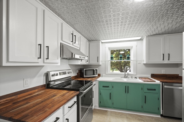 kitchen with butcher block countertops, stainless steel appliances, green cabinetry, white cabinetry, and sink