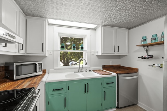 kitchen featuring white cabinetry, wall chimney range hood, appliances with stainless steel finishes, and sink