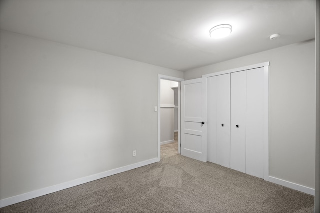 unfurnished bedroom with light colored carpet and a closet