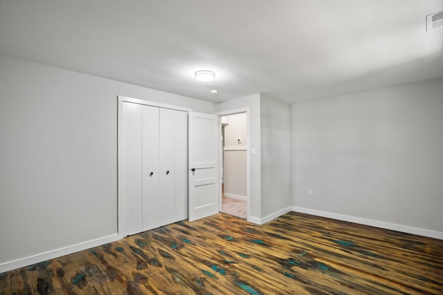 unfurnished bedroom with dark hardwood / wood-style floors and a closet