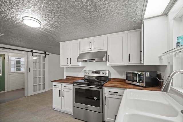 kitchen featuring stainless steel appliances, sink, white cabinetry, a barn door, and butcher block countertops