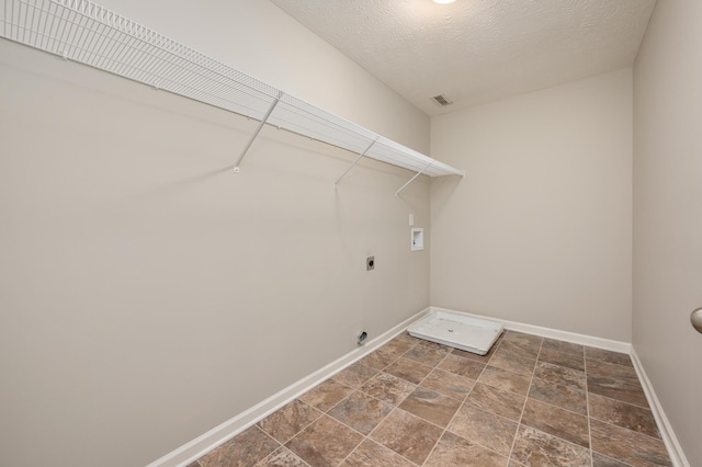 laundry room with washer hookup, hookup for an electric dryer, a textured ceiling, and dark tile flooring