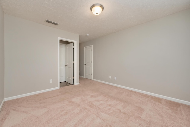 spare room with a textured ceiling and light colored carpet