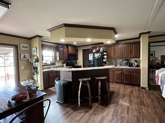 72 Golden Hollow Rd, Kelso, TN 37348 - kitchen featuring dark wood-type flooring, dark brown cabinets, a center island, black appliances, and a kitchen breakfast bar
