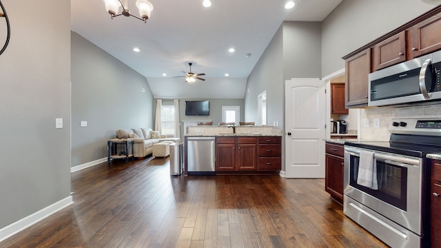 kitchen with dark hardwood / wood-style floors, light stone counters, stainless steel appliances, tasteful backsplash, and ceiling fan with notable chandelier