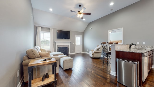 living room with a tile fireplace, ceiling fan, lofted ceiling, dark hardwood / wood-style floors, and sink