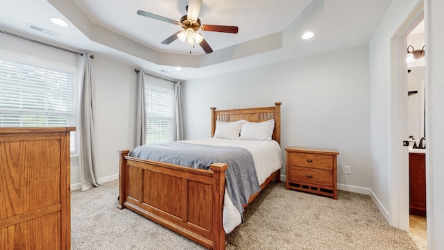 carpeted bedroom featuring a tray ceiling and ceiling fan