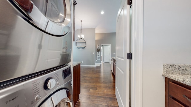 clothes washing area featuring dark hardwood / wood-style flooring and stacked washer / drying machine