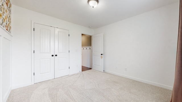 unfurnished bedroom featuring light colored carpet and a closet