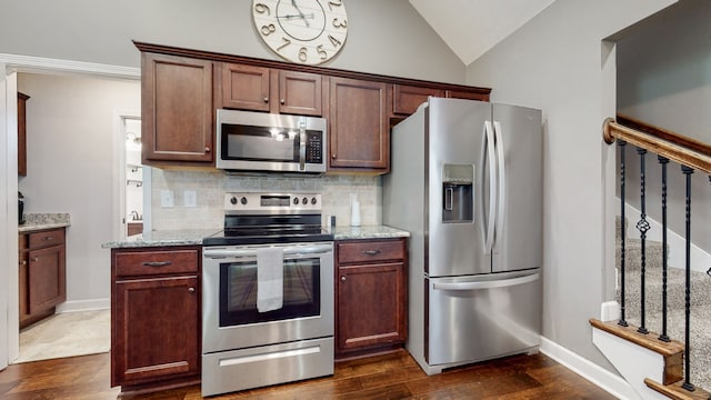 kitchen with light stone counters, tasteful backsplash, dark hardwood / wood-style floors, stainless steel appliances, and vaulted ceiling