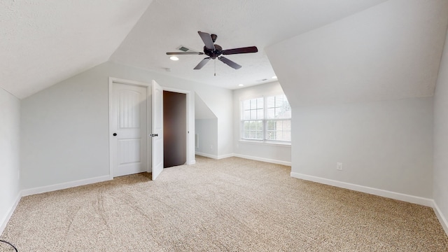 additional living space featuring light carpet, vaulted ceiling, ceiling fan, and a textured ceiling