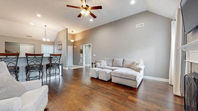 living room with a tiled fireplace, dark wood-type flooring, high vaulted ceiling, and ceiling fan with notable chandelier