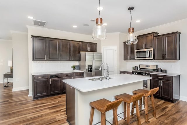 kitchen featuring hanging light fixtures, a kitchen island with sink, appliances with stainless steel finishes, sink, and dark hardwood / wood-style flooring