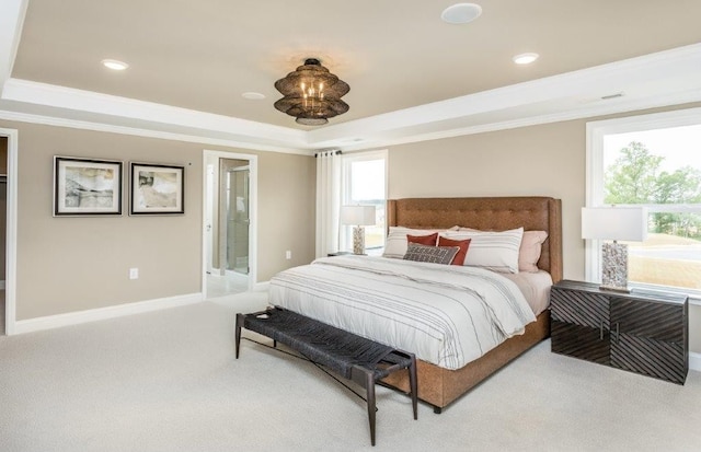 carpeted bedroom with connected bathroom, multiple windows, and a raised ceiling