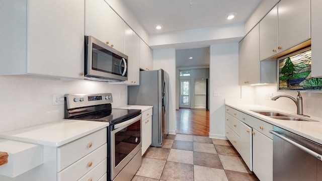 kitchen with sink, light tile floors, backsplash, stainless steel appliances, and white cabinetry