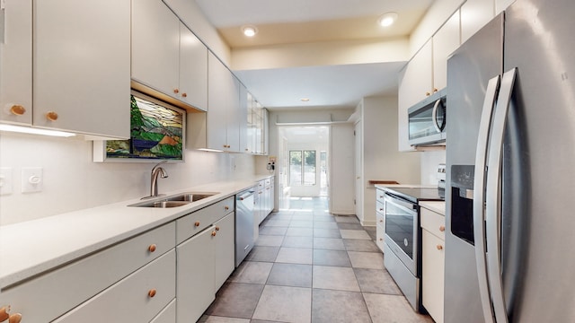 kitchen featuring white cabinetry, appliances with stainless steel finishes, light tile floors, and sink