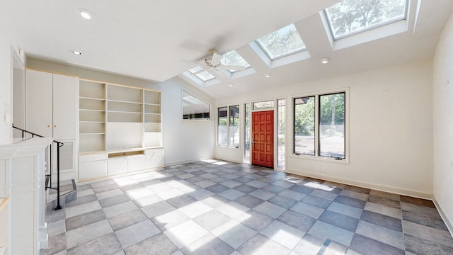 tiled empty room with vaulted ceiling with skylight and ceiling fan