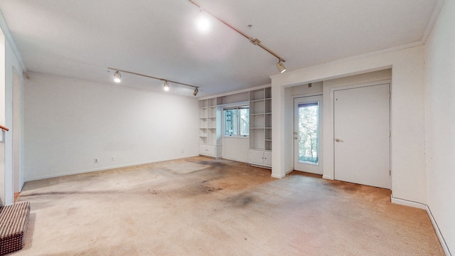 foyer with ornamental molding, track lighting, and light carpet