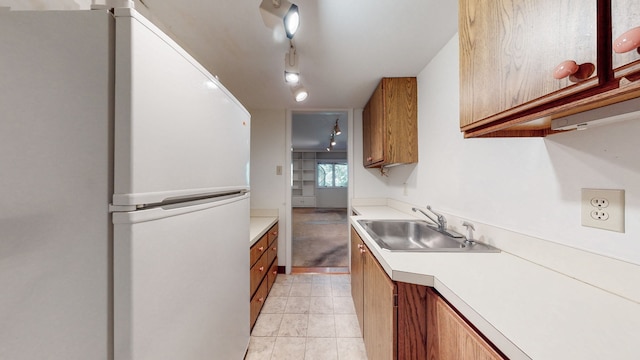 kitchen with light tile flooring, white fridge, and sink