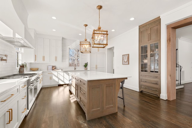 kitchen featuring a kitchen breakfast bar, white cabinets, a center island, dark wood-type flooring, and range with two ovens