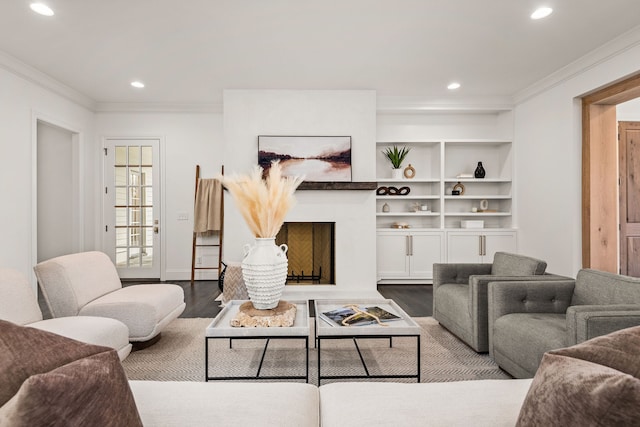 living room featuring crown molding, built in shelves, and light wood-type flooring