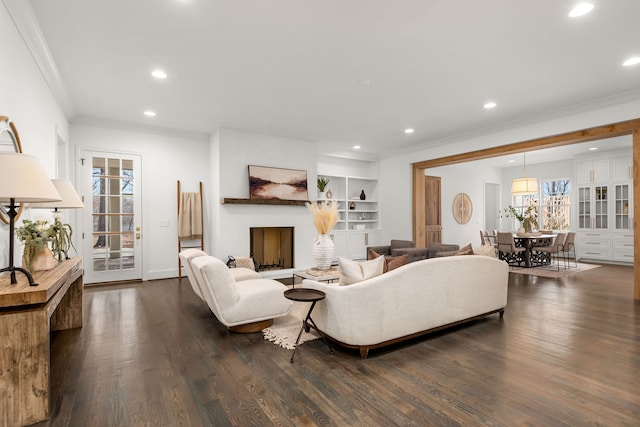 living room featuring crown molding, built in features, and dark hardwood / wood-style flooring