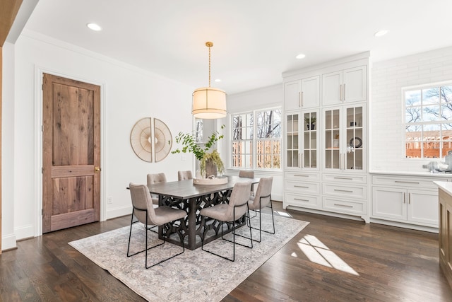 dining area with ornamental molding and dark wood-type flooring