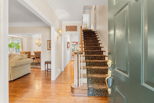 stairway featuring a notable chandelier, light hardwood / wood-style flooring, and crown molding