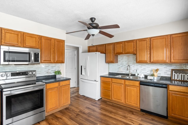 kitchen with dark hardwood / wood-style flooring, tasteful backsplash, stainless steel appliances, ceiling fan, and sink