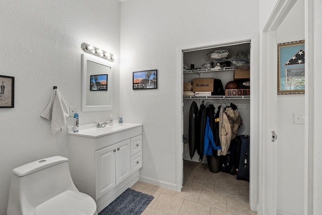 bathroom with toilet, tile flooring, and vanity