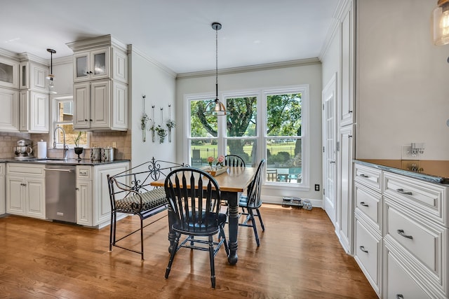 dining space featuring crown molding, sink, and hardwood / wood-style flooring