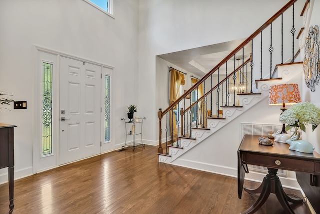 foyer featuring a notable chandelier, a high ceiling, plenty of natural light, and hardwood / wood-style flooring