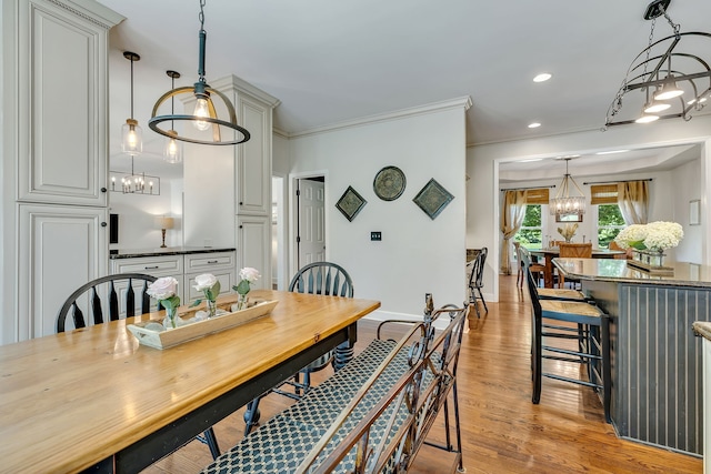 dining area featuring crown molding, a notable chandelier, and light hardwood / wood-style floors