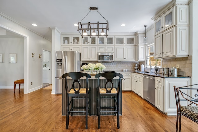 kitchen with decorative light fixtures, light hardwood / wood-style floors, stainless steel appliances, a chandelier, and a kitchen island