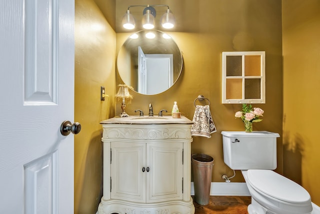 bathroom with large vanity, toilet, and hardwood / wood-style flooring